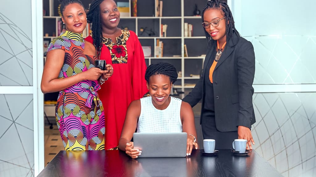 Quatre jeunes femmes travaillent ensemble autour d'un ordinateur portable