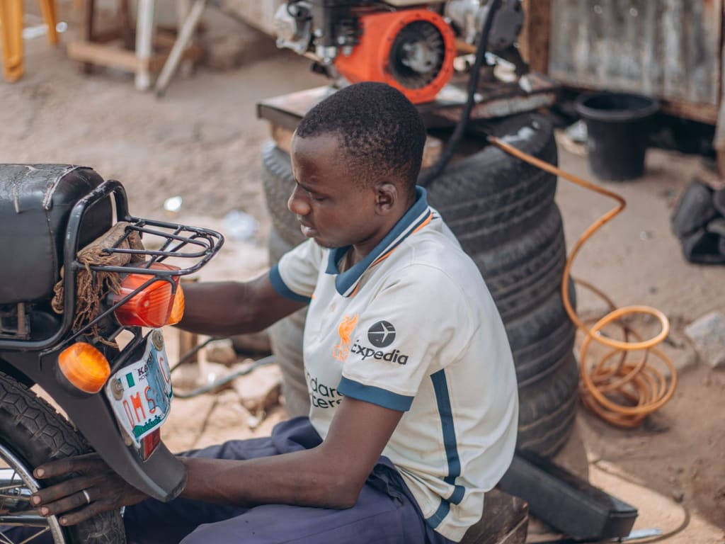 Un jeune mécanicien répare une moto